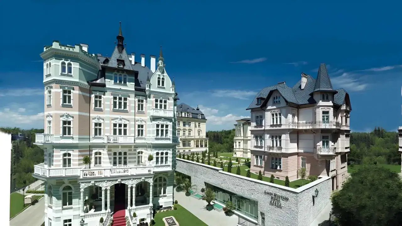 Eleganckie budynki w stylu secesyjnym, przypominające pałace, otoczone zielenią. To piękne Karlowe Wary, gdzie historia spotyka się z luksusem.
