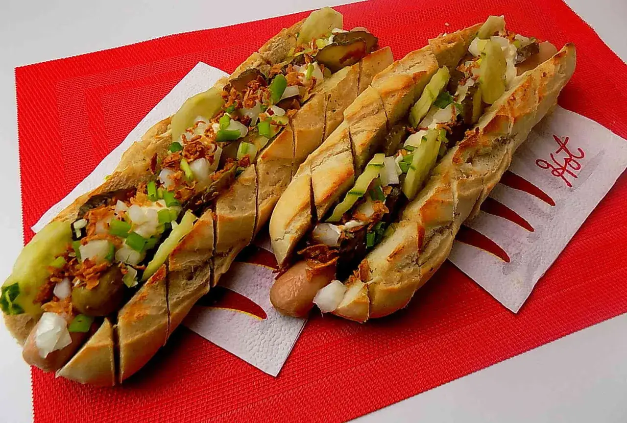 Dwa pyszne, domowe hot dogi z chrupiącą bułką, kiełbaską, og&oacute;rkiem, cebulką i chrupiącą cebulką.