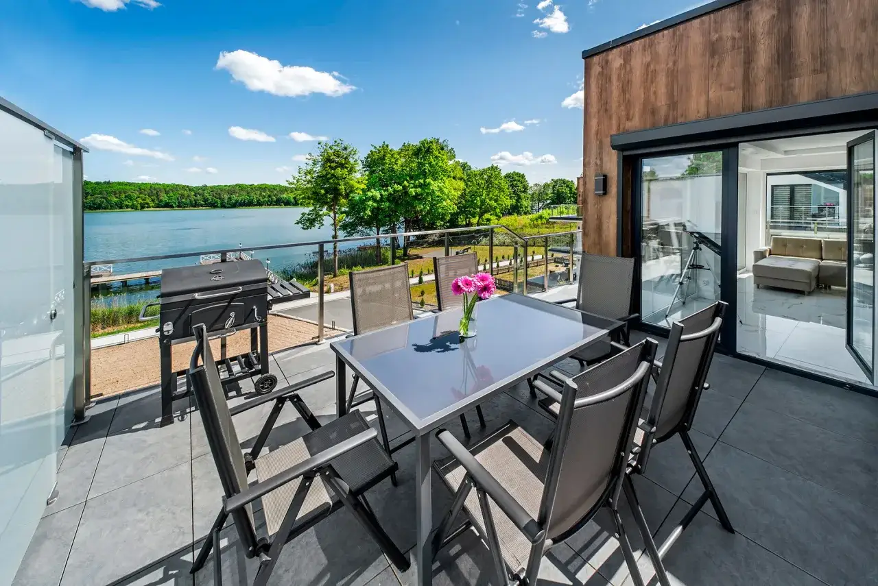 Taras z grillem i stołem, widok na jezioro. Idealne miejsce na relaks w hotelu Mikołajki Leisure & Spa.