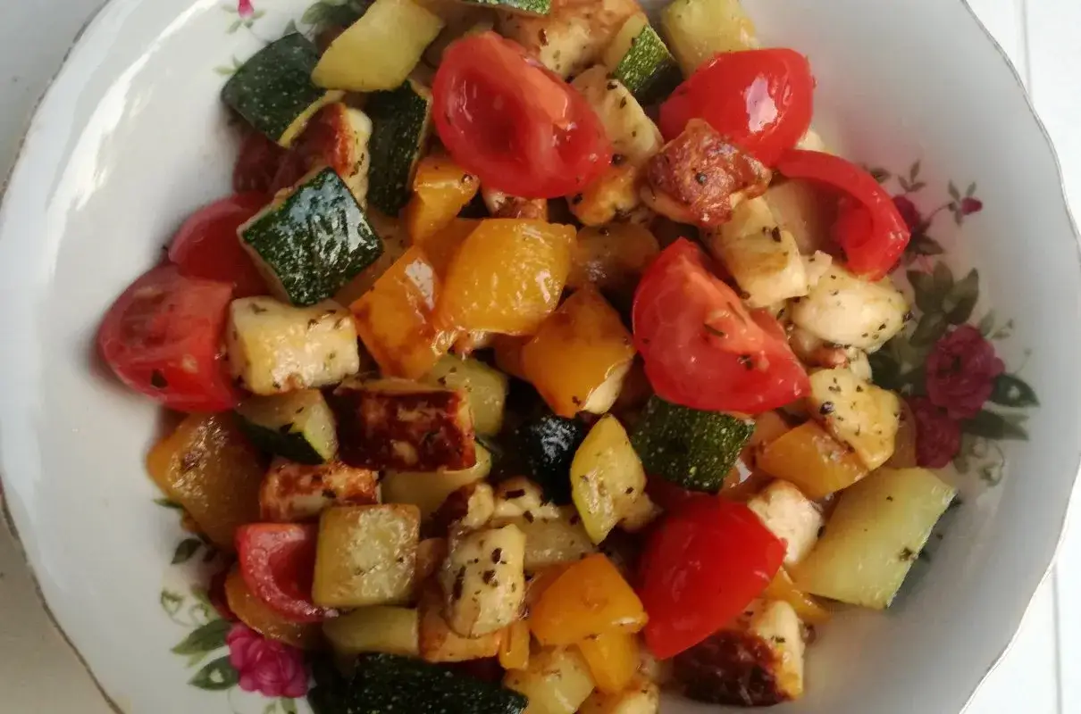 Kolorowa sałatka z grillowanymi warzywami i ser halloumi, podana w talerzu z kwiatowym wzorem.