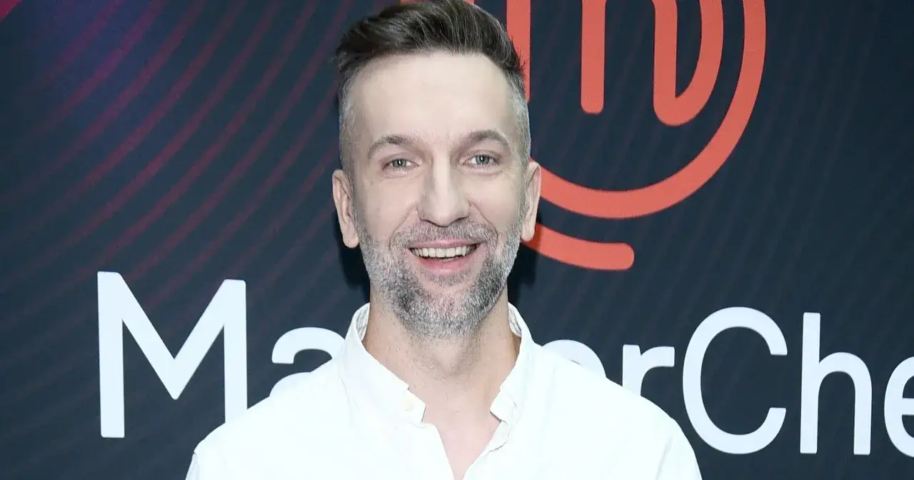 Uśmiechnięty Przemek Klima na tle logo MasterChef.