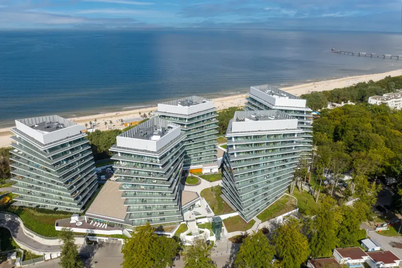 Nowoczesny wave resort z tarasami i widokiem na morze. Architektura idealnie wkomponowana w nadmorski krajobraz.