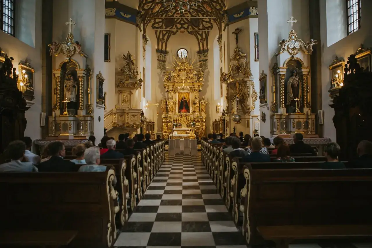 Wnętrze kościoła z ołtarzem i ławkami pełnymi wiernych. To jeden z najpiękniejszych kościołów w Polsce, zachwycający złotymi zdobieniami.